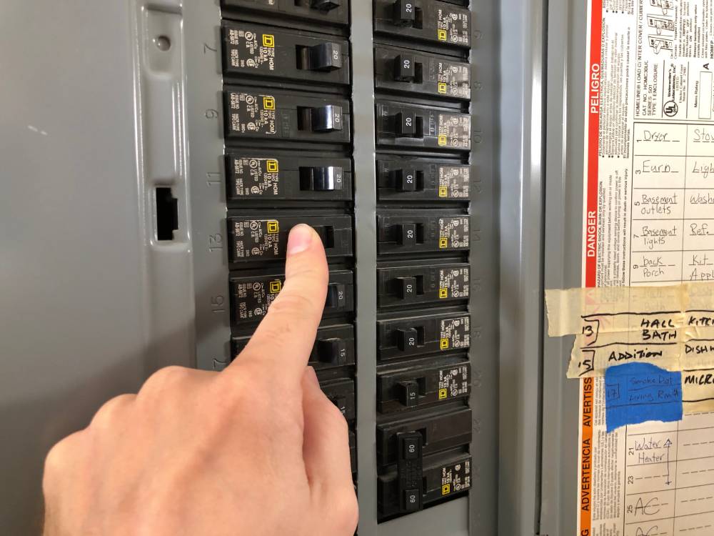 Finger pointing at electrical panel and circuit breaker